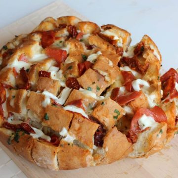 Stuffed pizza bread on a wooden chopping board.