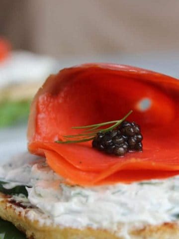 Caviar placed in side a roll of salmon on top of some cream cheese and toasted bread.