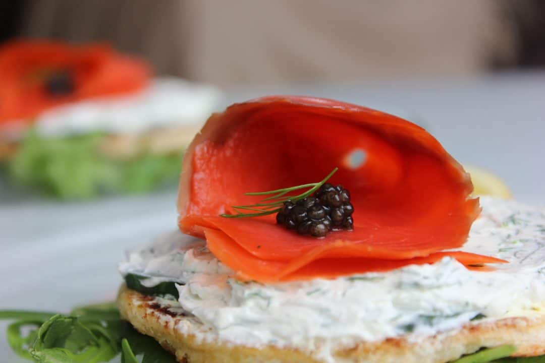 Caviar placed in side a roll of salmon on top of some cream cheese and toasted bread.