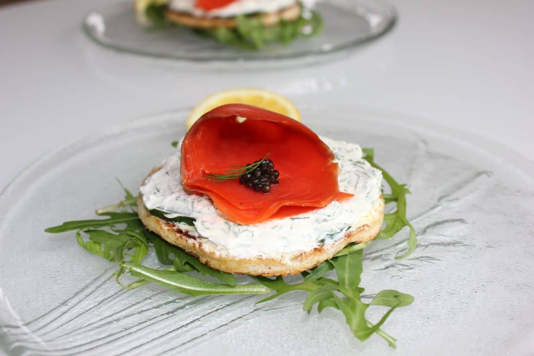 A salmon caviar appetizer served on a bed of arugula on a glass plate.