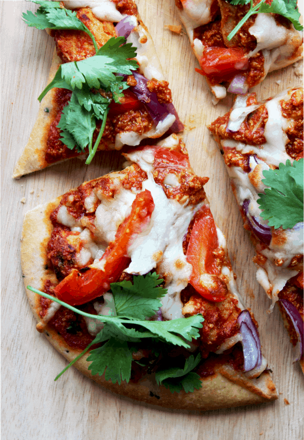 Naan bread pizza on a wooden chopping board