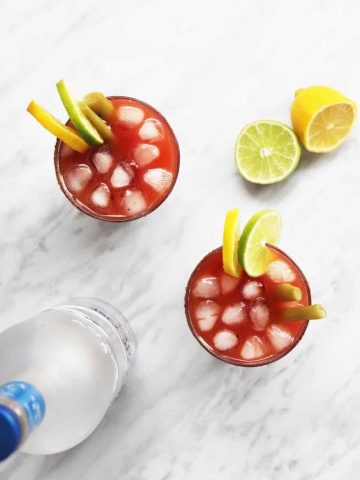 A top shot of two caesar drinks with lemon and lime garnish