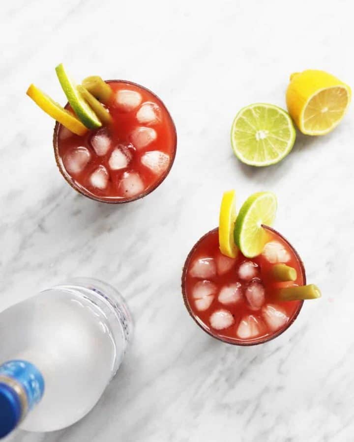 A top shot of two caesar drinks with lemon and lime garnish