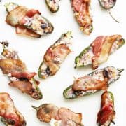 Overhead shot of a white board with sweet jalapeno peppers wrapped in bacon
