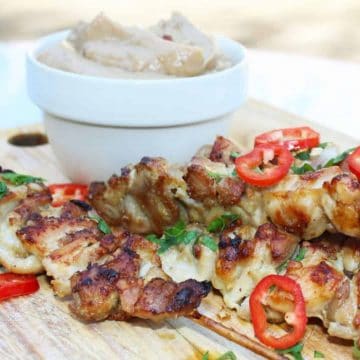 skewers of crispy chicken satay with peanut dipping sauce on a wooden serving board