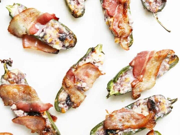 Overhead shot of a white board with sweet jalapeno peppers wrapped in bacon