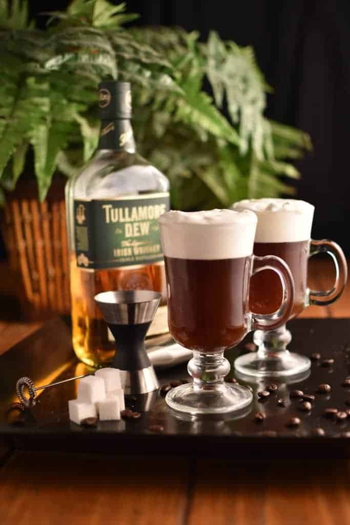 Two glasses of Irish coffee with a bottle of whiskey