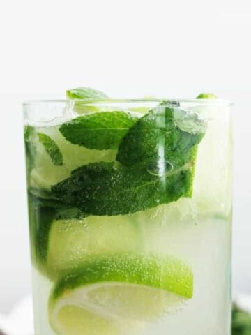 A closeup of a mojito elderflower cocktail on a white background