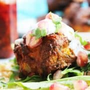 A closeup of a lamb meatball with tzatziki and pomegranate seeds