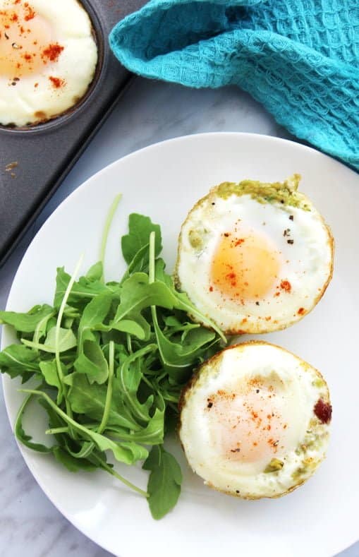 Top down shot of two bacon and egg cups on a white plate