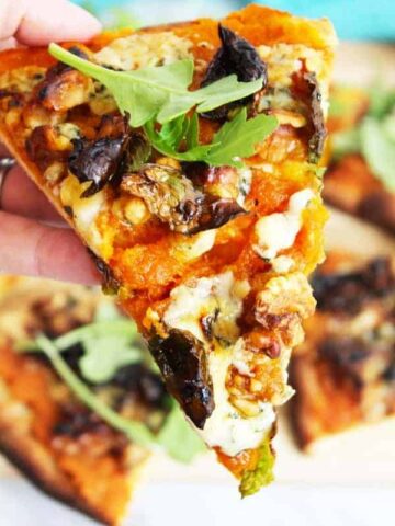 A close up of a slice of blue cheese pizza with pumpkin