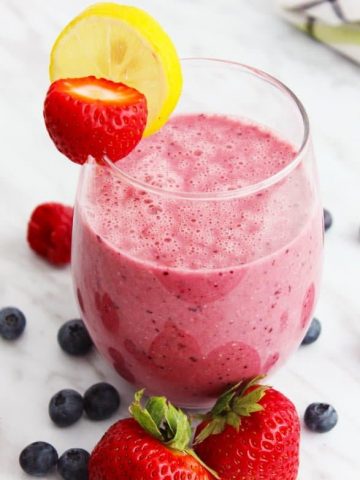 A berry oat smoothie garnished with a lemon slice and strawberry