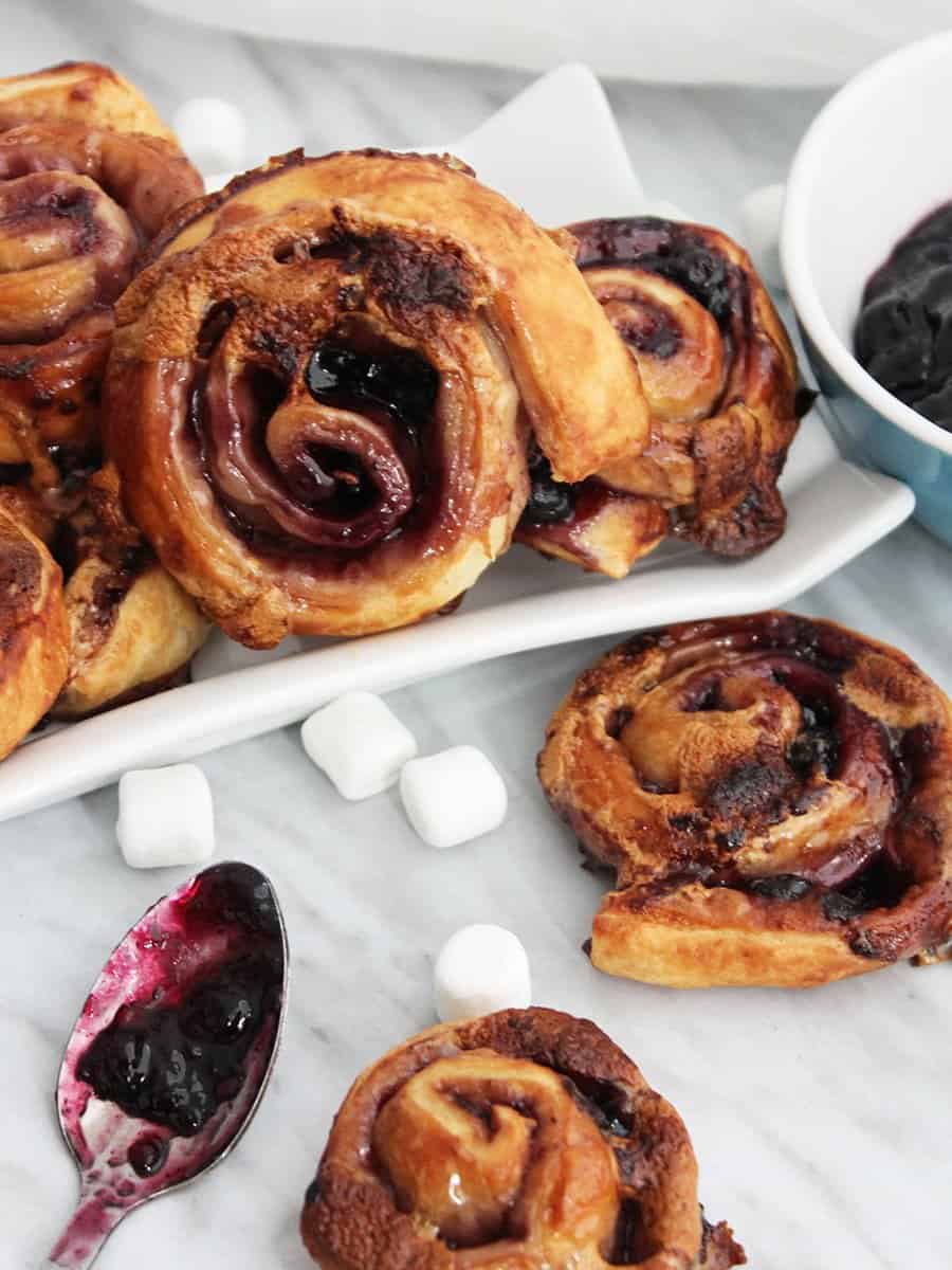 Close up of a sweet puff pastry pinwheel next to a spoon with jam