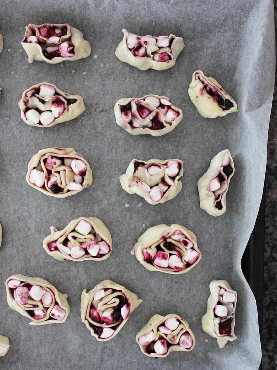 Uncooked sweet puff pastry pinwheels on parchment