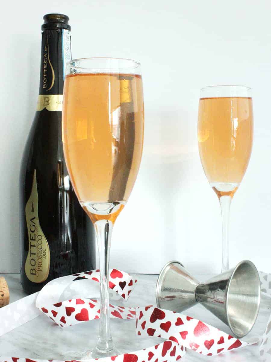Two glasses of a prosecco brunch cocktail with a red ribbon