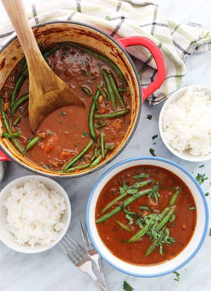 Beef curry stew with coconut milk in a large pot with wooden spoon
