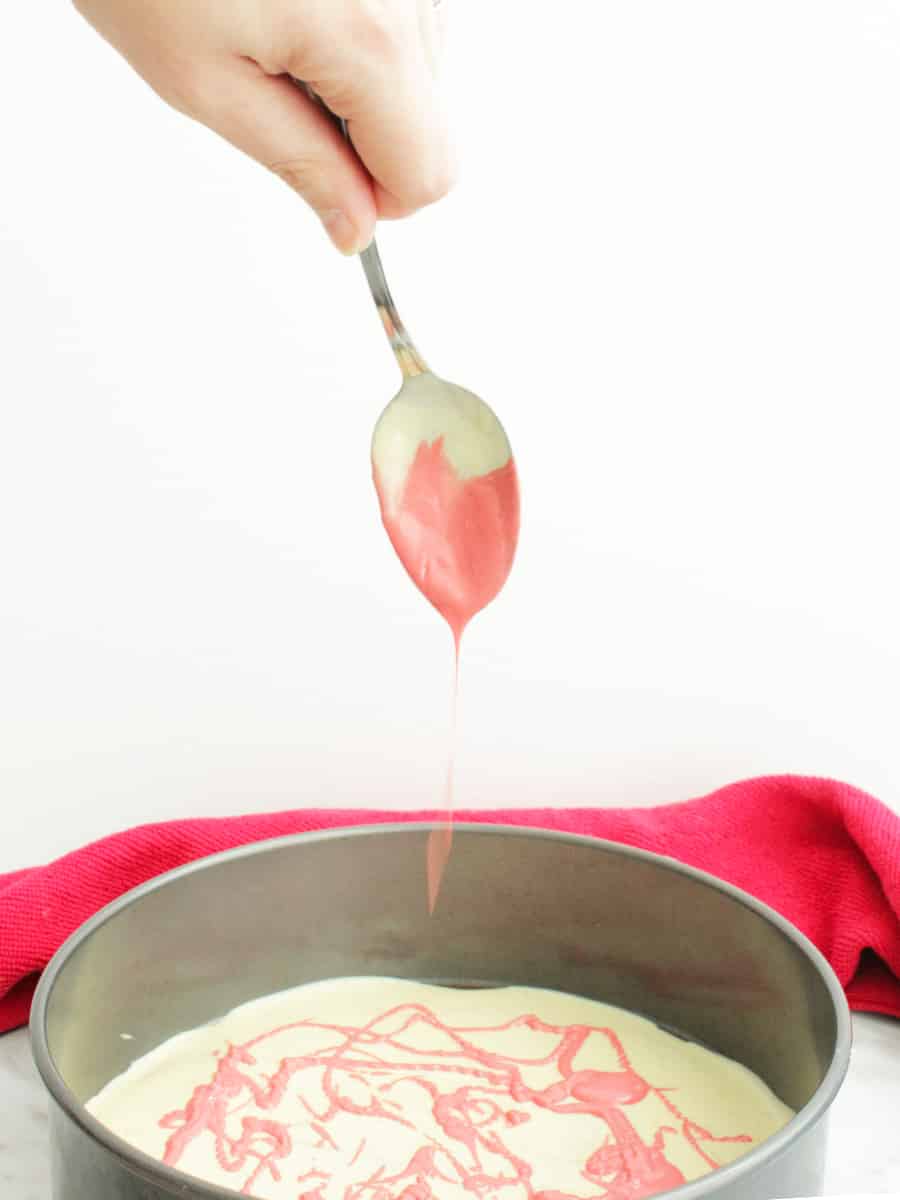 Pink melted chocolate being dripped on to white chocolate