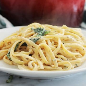 Close up of creamy garlic one pot pasta on a white plate