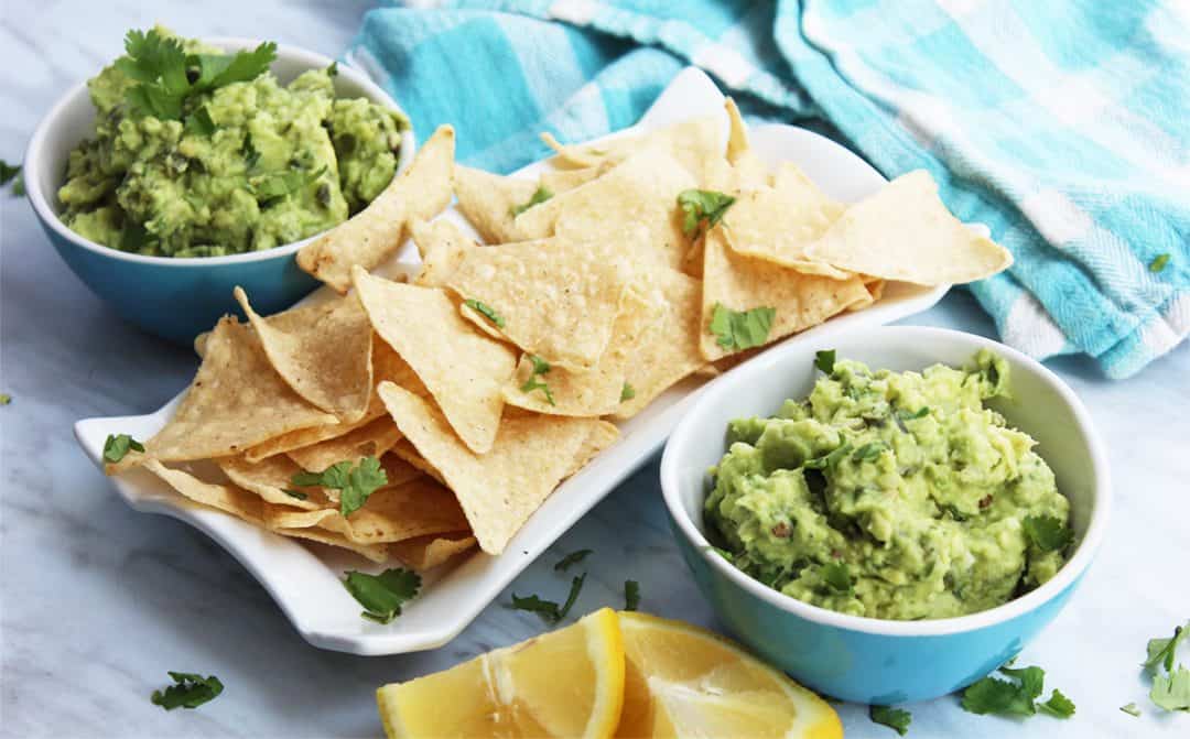 Two bowls of jalapeno guacamole next to tortilla chips