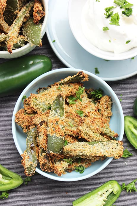 Top shot of crispy jalapeno fries in a blue bowl with sour cream dip