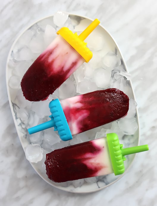 Three cherry and yogurt popsicles on a plate of ice