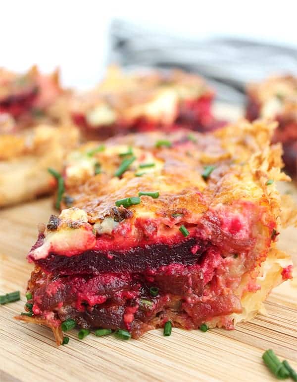 A slice of beetroot tart on a wooden chopping board