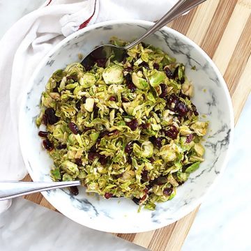Sauteed Brussels sprouts in white bowl with two serving spoons