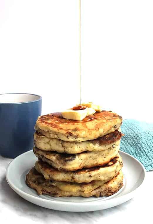 A stack of savory pancakes on a plate with maple syrup being drizzled on top