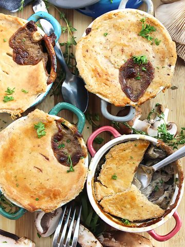 Four mushroom pot pies on a wooden chopping board