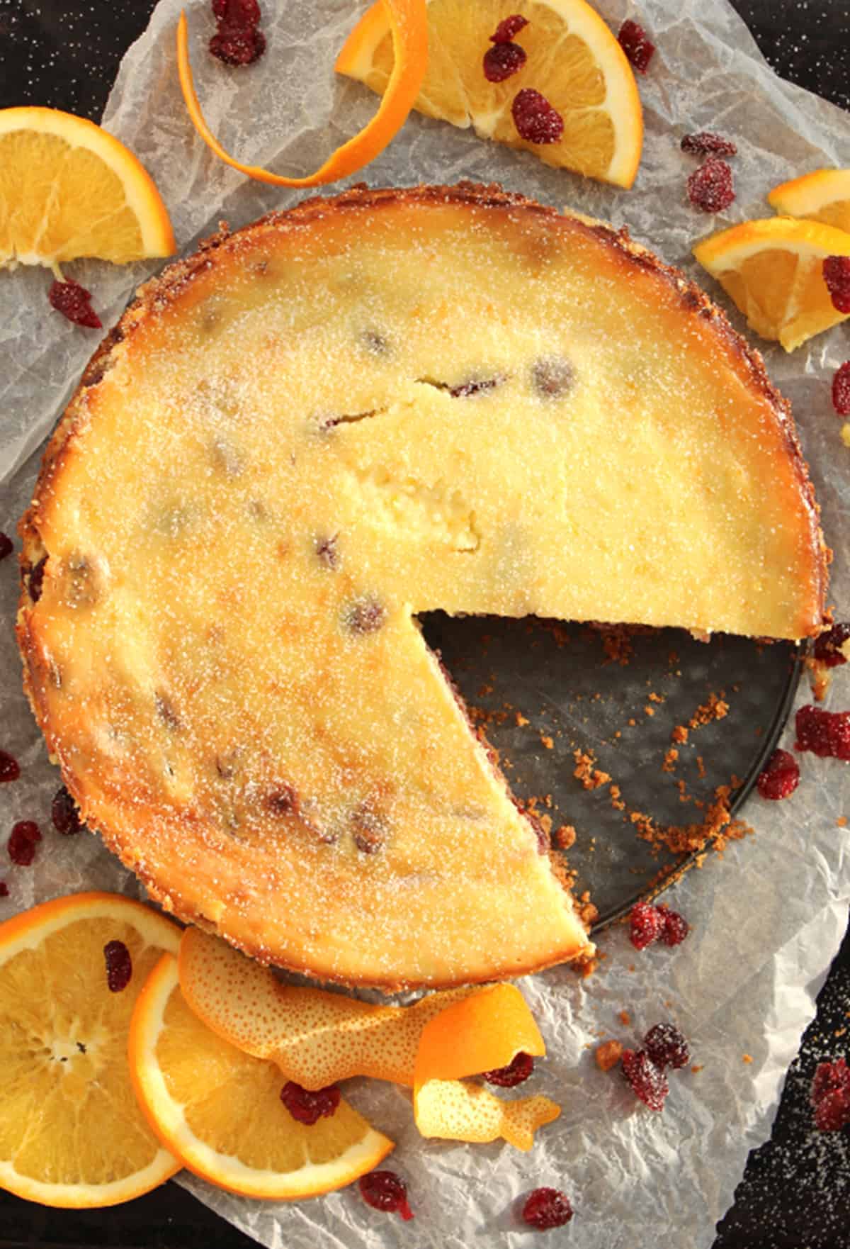 A cranberry and orange cheesecake with a slice cut of of it
