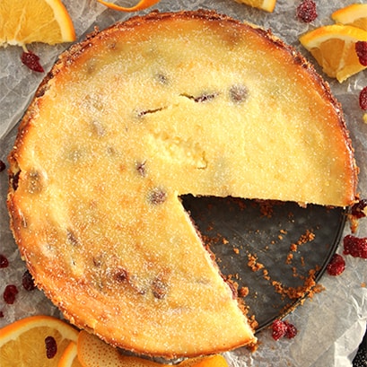 A cranberry and orange cheesecake with a slice cut out of it