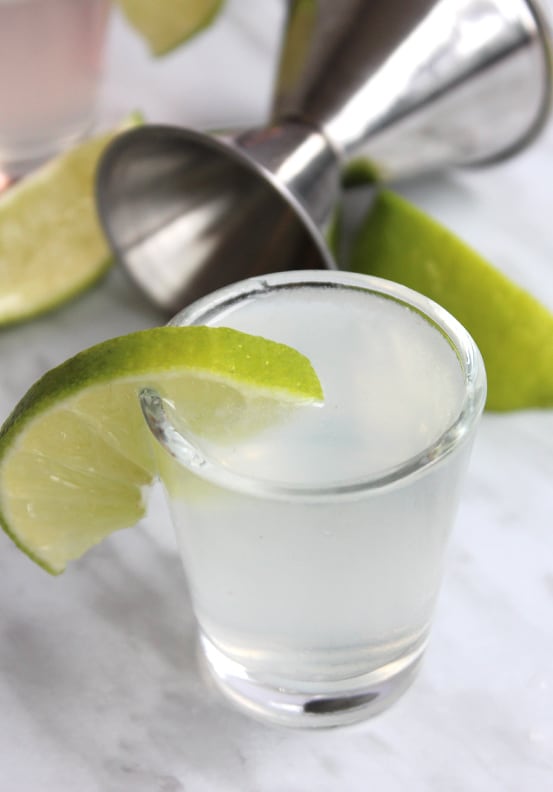 A gin shot with lime garnish ready to serve