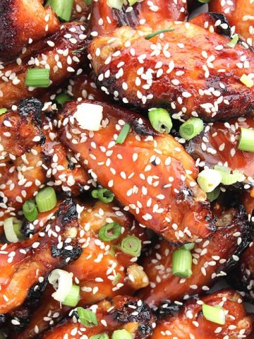 Close up of the sticky chicken wings with a honey and sriracha glaze sprinkled with sesame seeds