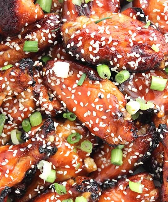 Close up of the sticky chicken wings with a honey and sriracha glaze sprinkled with sesame seeds