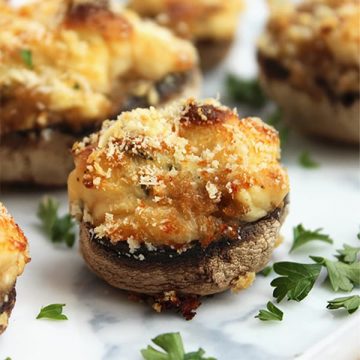 A stuffed mushroom on a plate garnished with herbs