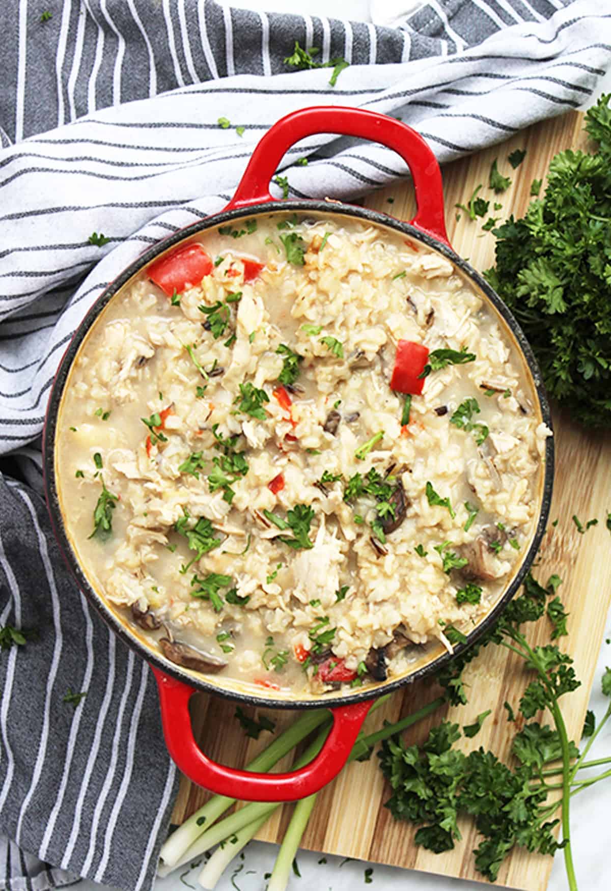 Chicken and rice soup in a red dutch oven on a chopping board