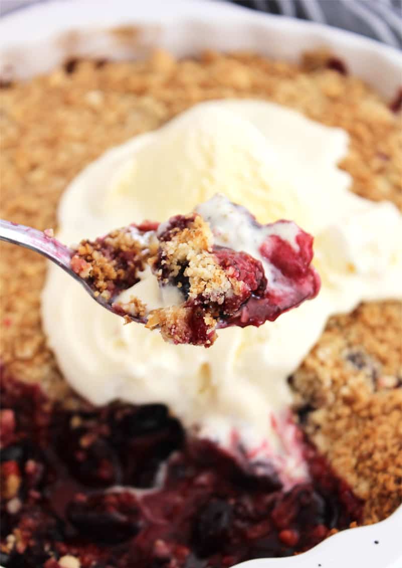 Blackberry and cherry crumble on a spoon