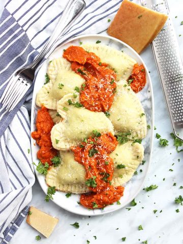 Heart shaped ravioli served with red sauce on a large oval plate