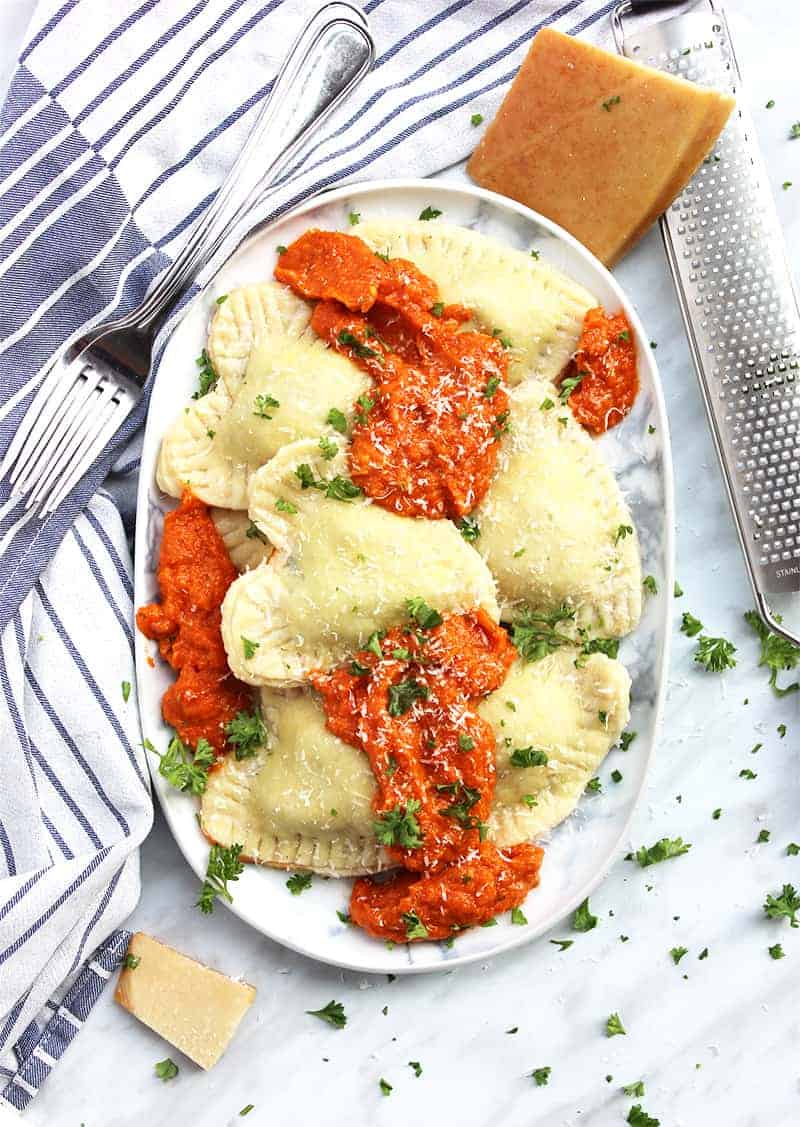 Heart shaped ravioli served with red sauce on a large oval plate