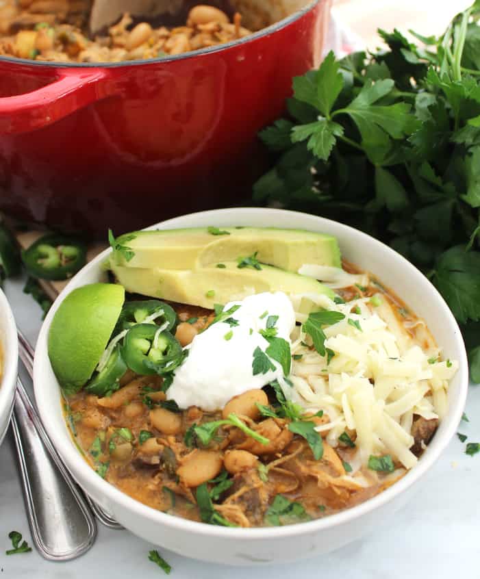 White bean chili topped with avocado, shredded cheese, sour cream and jalapenos