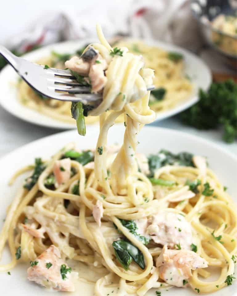 A fork lifting up the lemon salmon pasta from a plate