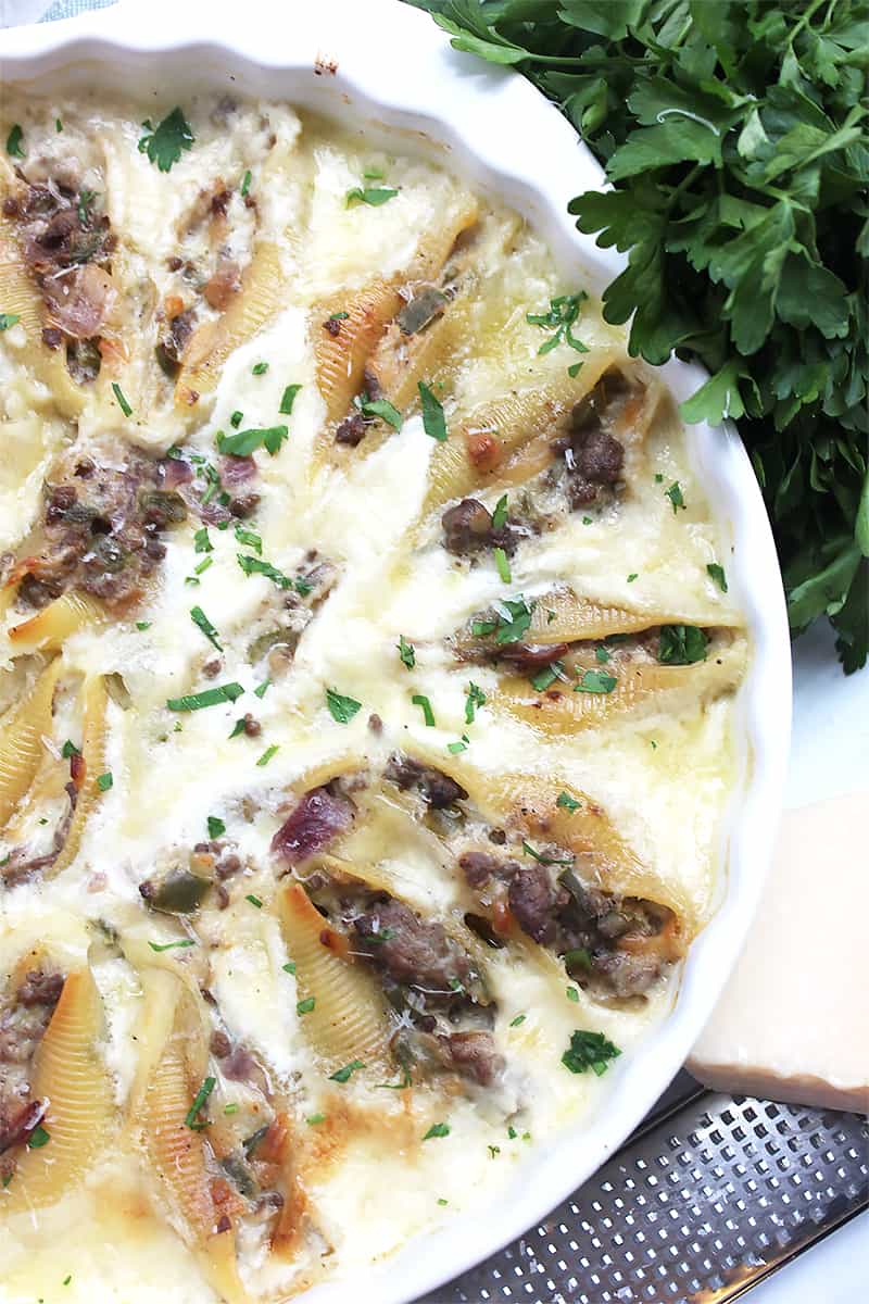 Philly cheesesteak stuffed shells next to a bunch of fresh parsley