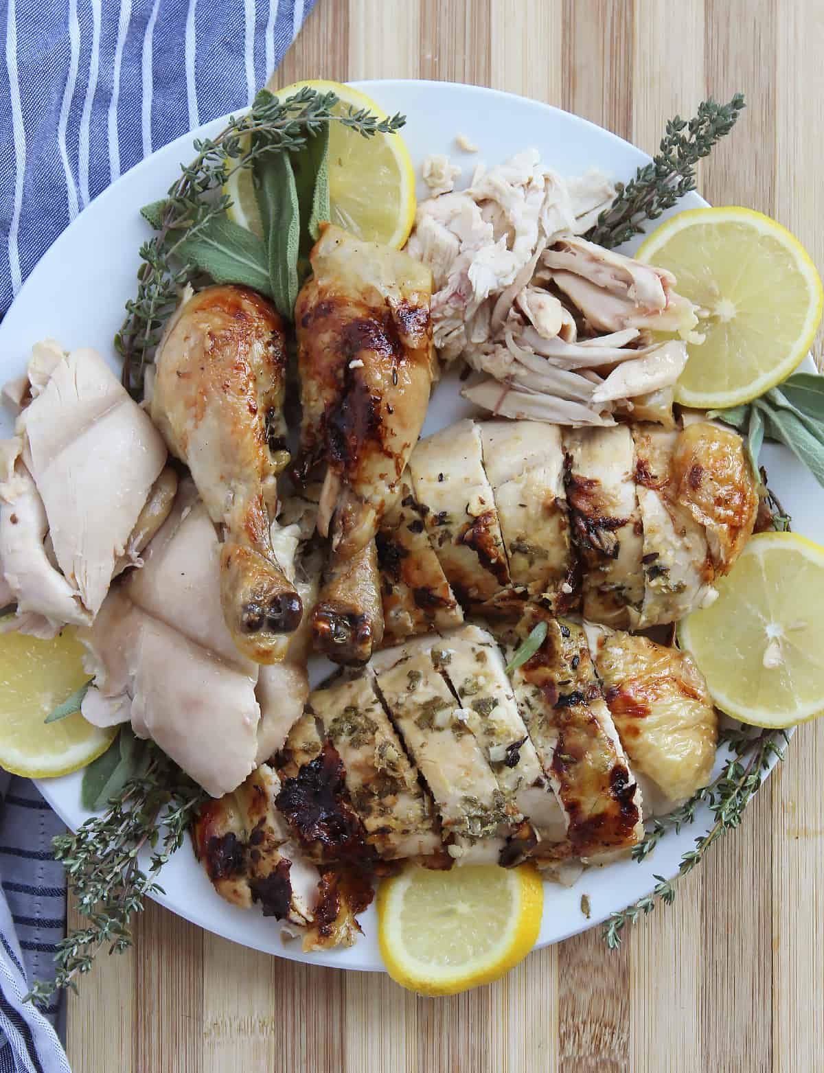 Pieces of slow roasted chicken on a plate with lemon and herbs