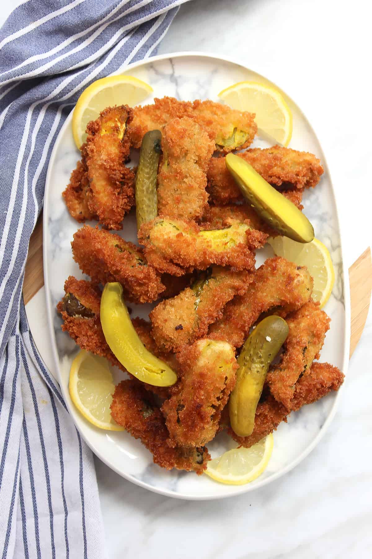 Overhead shot of fried dill pickles on a plate with lemon slices
