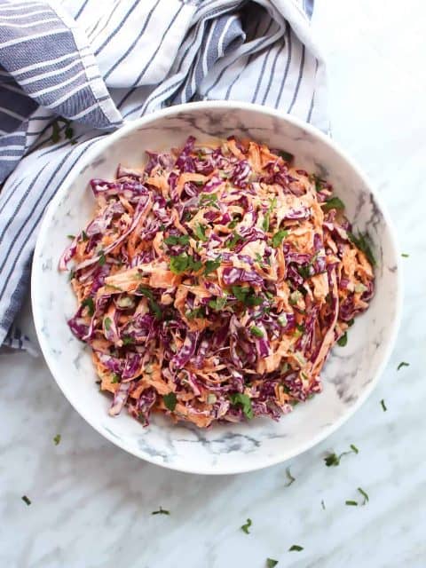Overhead shot of red cabbage and carrot slaw in a large white bowl