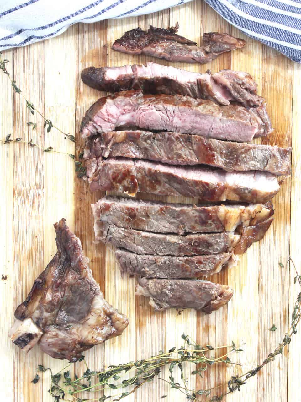 Coffee steak cut into slices next to sprigs of fresh thyme