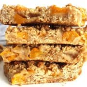 Close up of four peach oatmeal bars stacked on top of each other