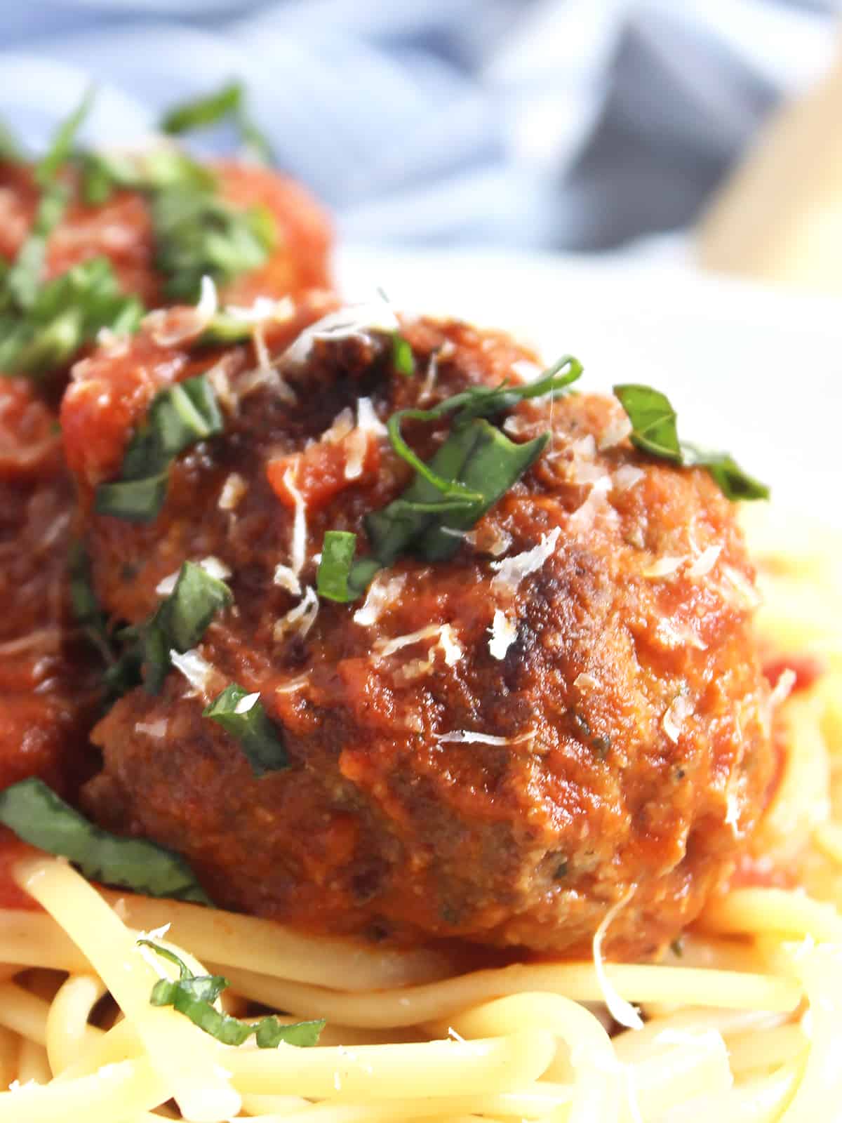Close up of a bison meatball with grated parmesan and herbs