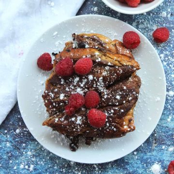 Chocolate French toast with a dusting of powdered sugar and fresh raspberries.