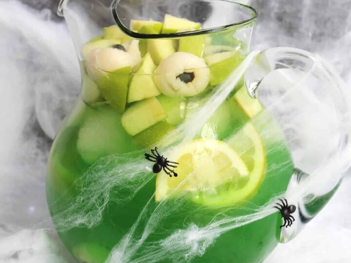 Halloween sangria in a large jusg decorated with cobwebs and plastic spiders.
